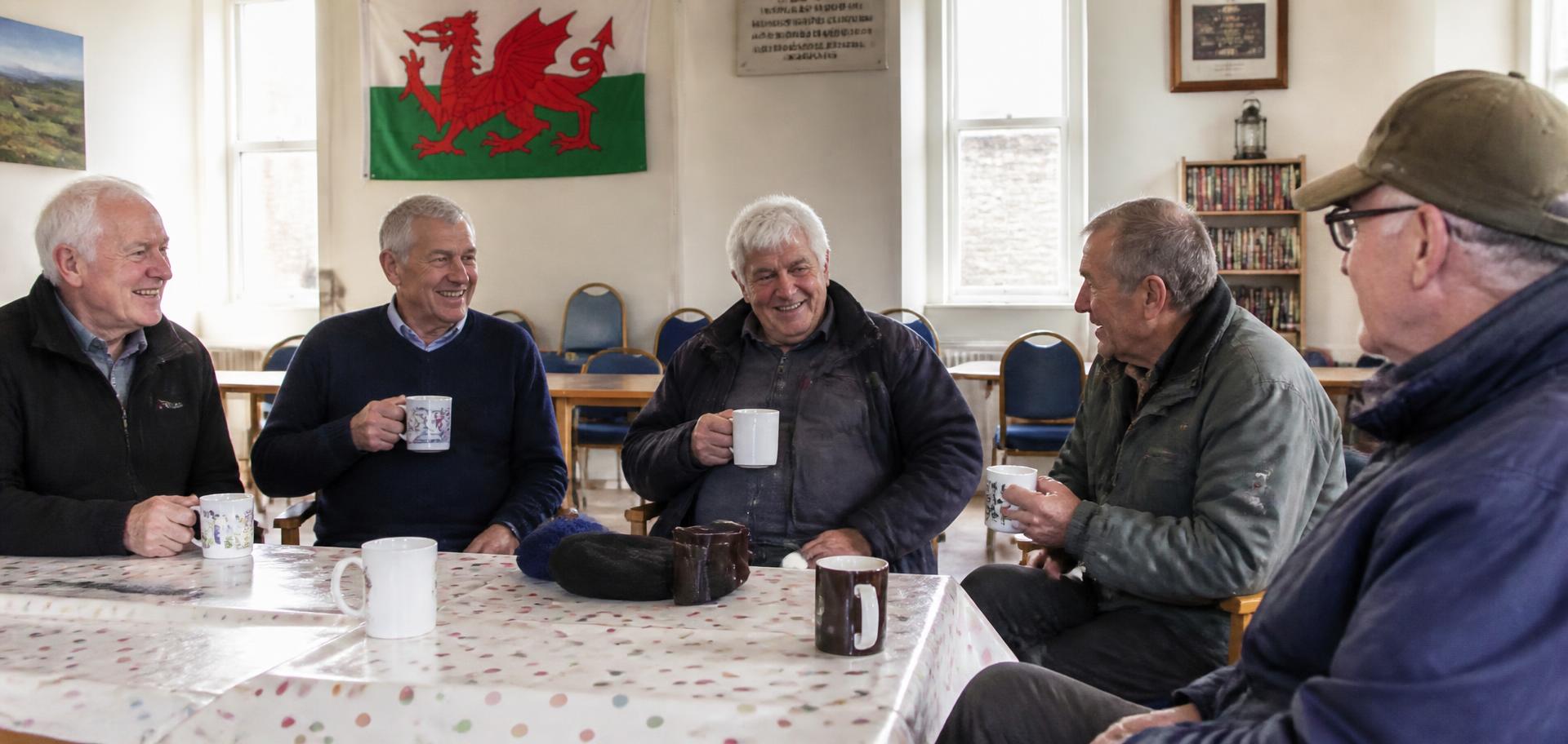 Members of the North Wales Prostate Cancer Support Group talking over cups of tea in a community hall